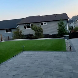 Professional hardscape installation services in Bothell showcasing a modern paver patio, spacious outdoor living area, artificial turf lawn, landscape lighting, and contemporary backyard hardscape design.